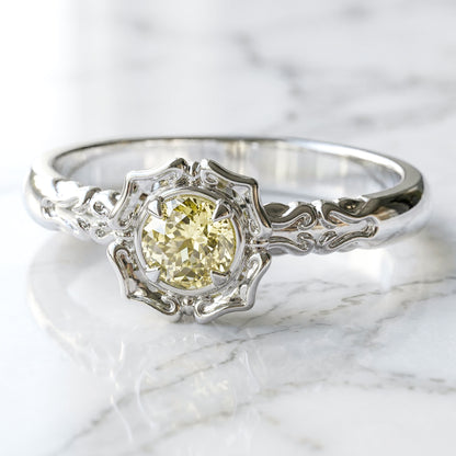 A lab created light yellow sapphire centerpiece engagement ring with a stylized flower petal setting, made of white gold.
