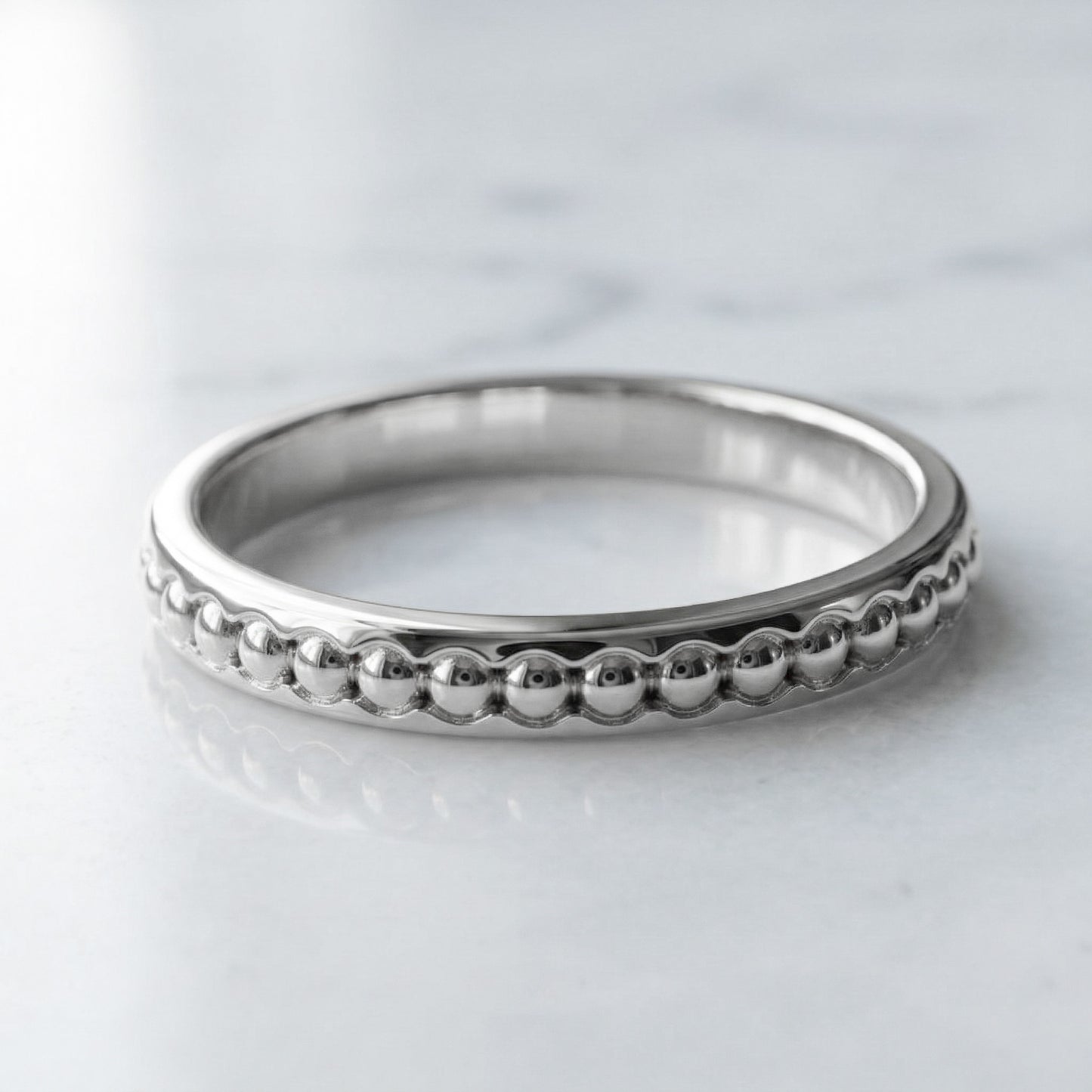 whit gold ring with beaded design on a light gray background