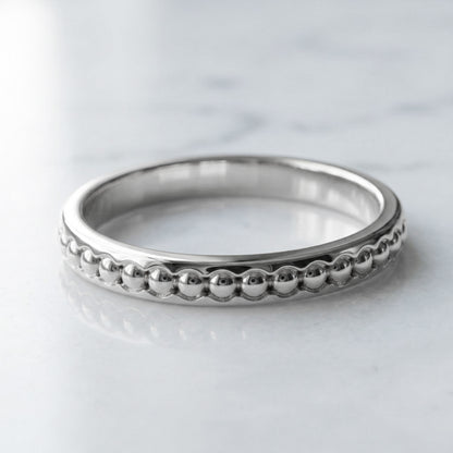 whit gold ring with beaded design on a light gray background