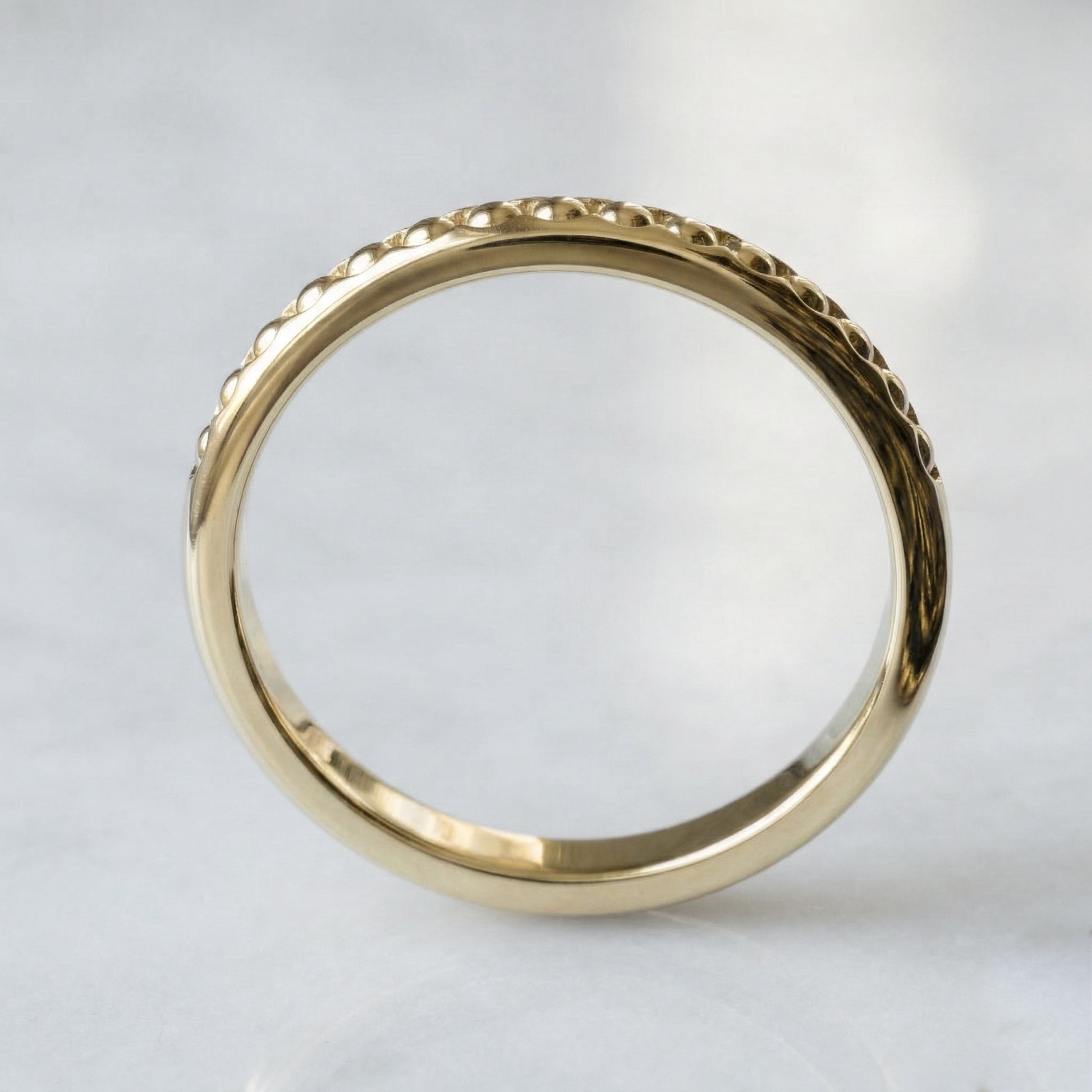 Gold ring with intricate design on a light gray background