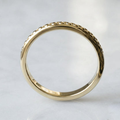 Gold ring with intricate design on a light gray background