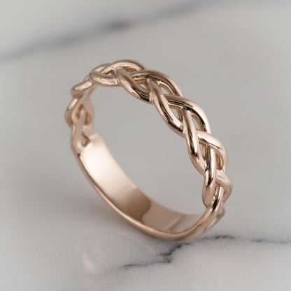 Rose gold braided ring on a marble surface