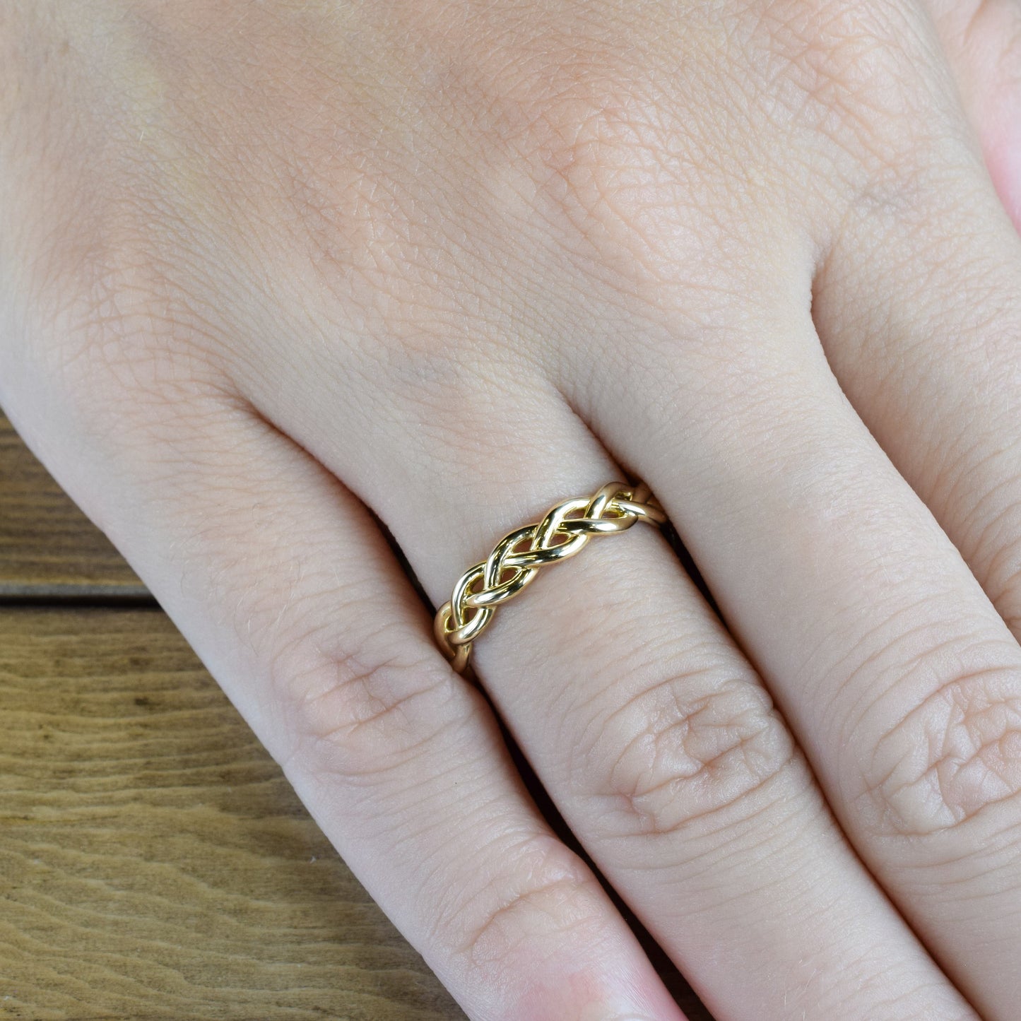 braided yellow gold band on finger