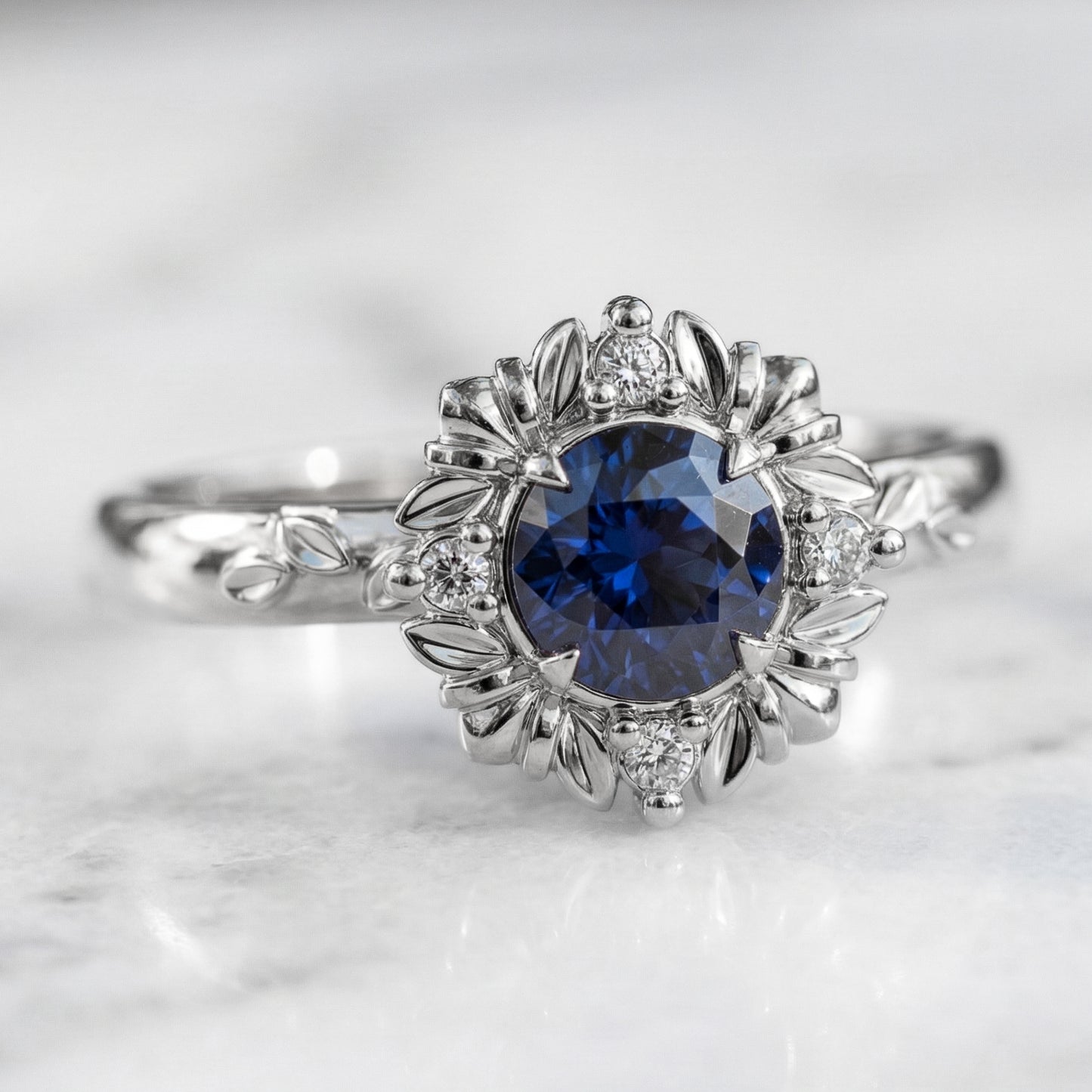 A round blue sapphire engagement ring with a gold and diamond halo setting