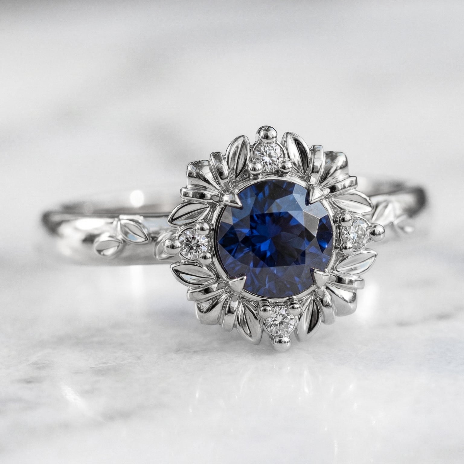 A round blue sapphire engagement ring with a gold and diamond halo setting