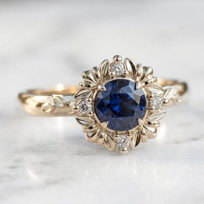 Gold ring with a blue gemstone and diamond accents on a light background