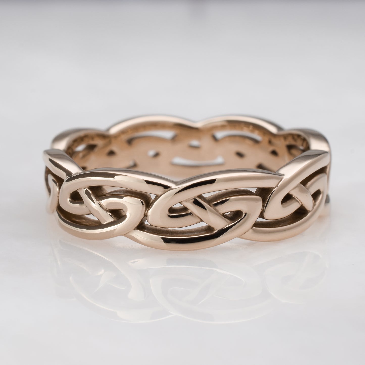 Rose gold Celtic knot ring on a light gray background