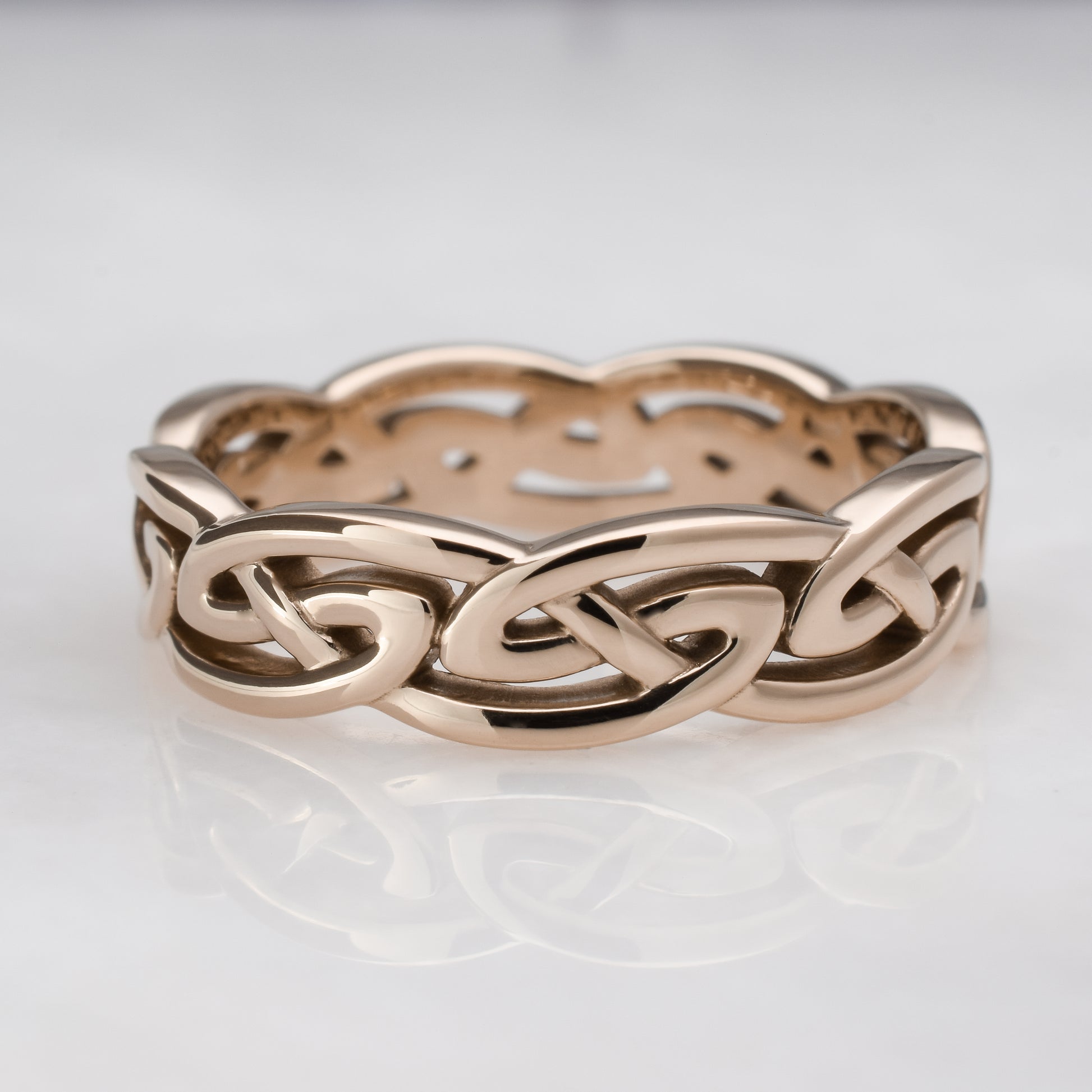 Rose gold Celtic knot ring on a light gray background