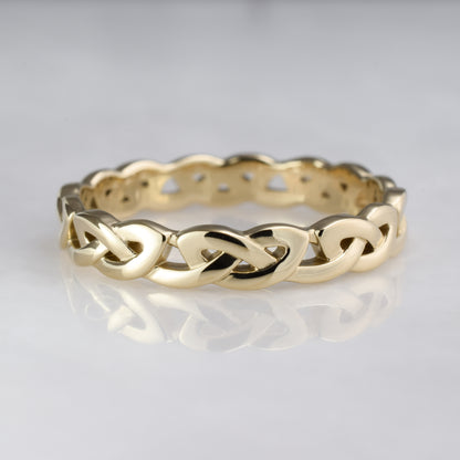 Gold braided ring on a reflective gray surface