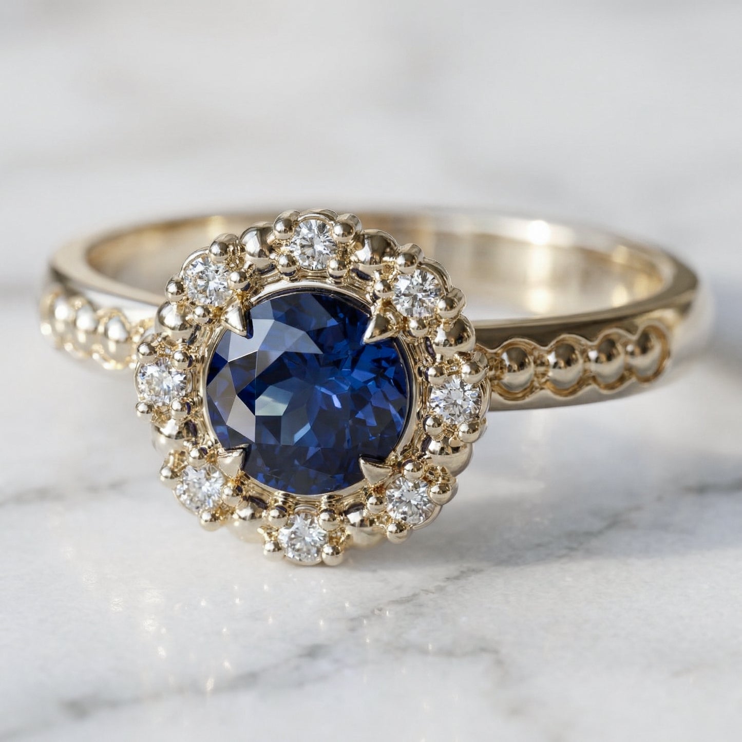 Blue sapphire with halo of diamonds and spheres engagement ring in yellow gold