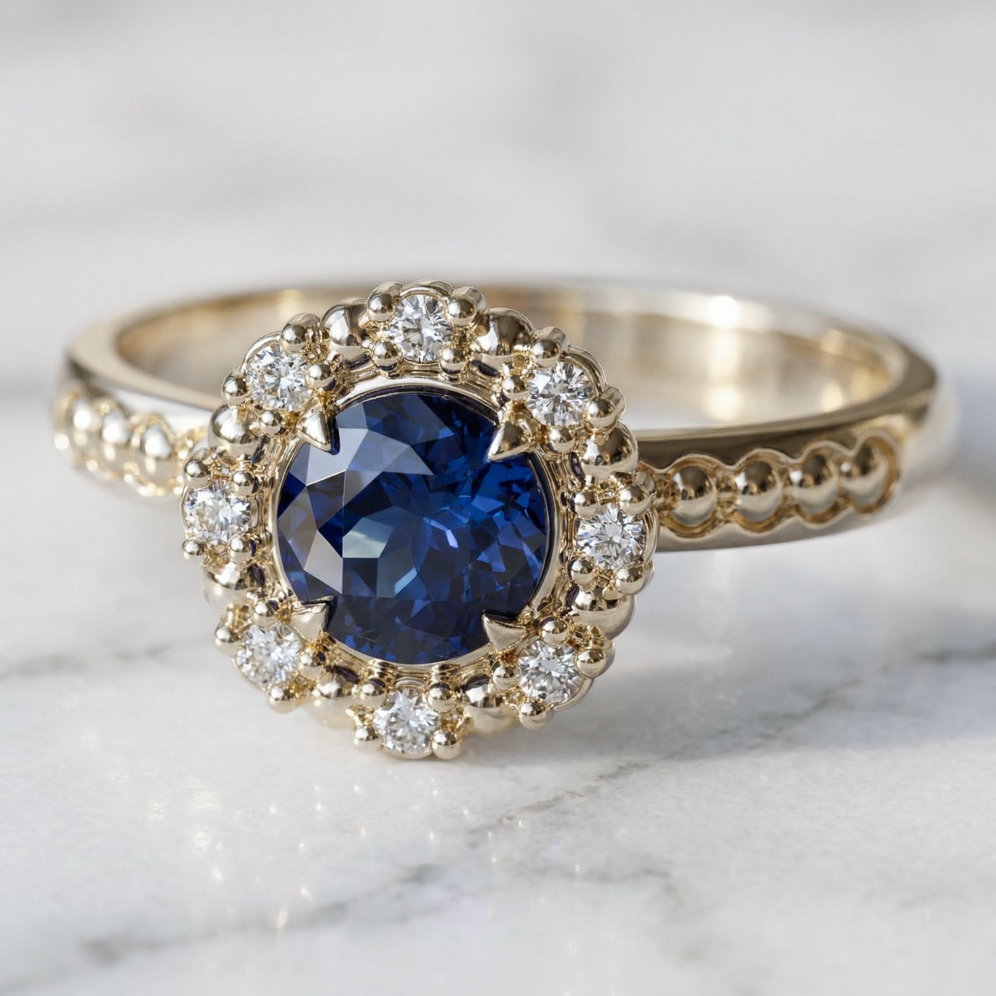 Blue sapphire with halo of diamonds and spheres engagement ring in yellow gold