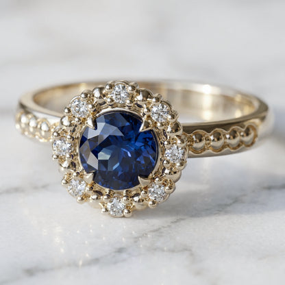 Blue sapphire with halo of diamonds and spheres engagement ring in yellow gold