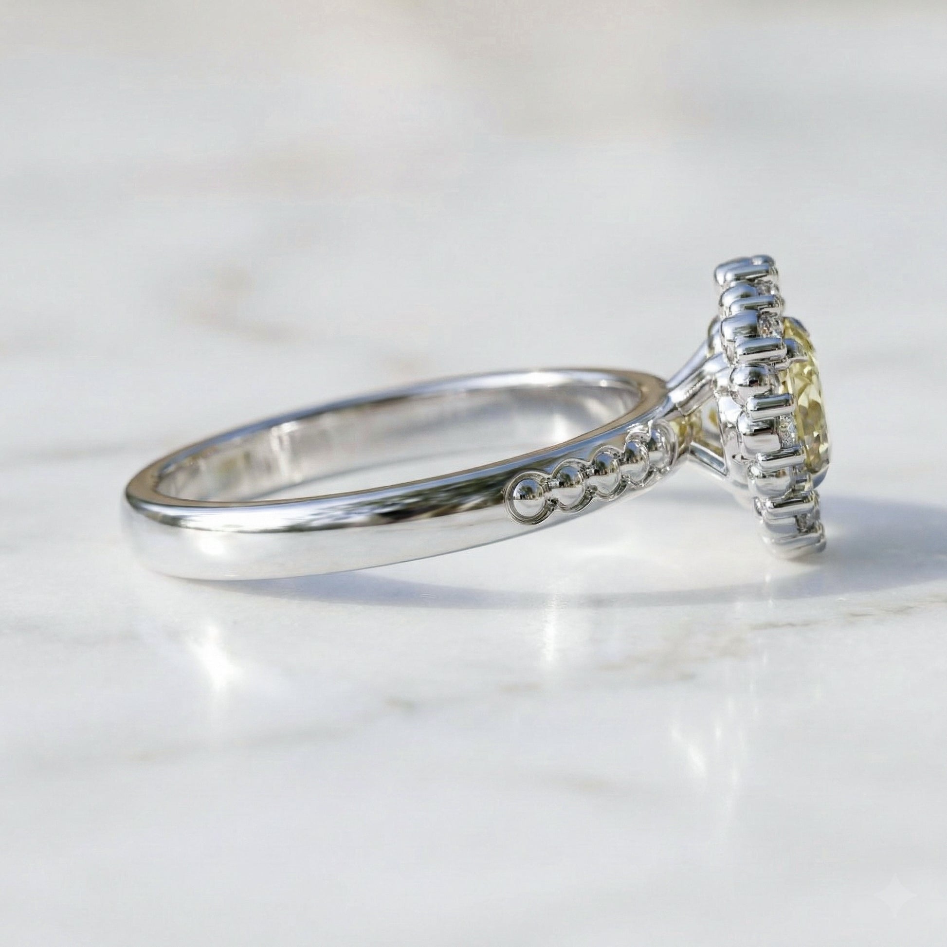 white gold ring with a yellow gemstone on a light background