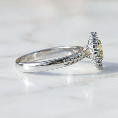 white gold ring with a yellow gemstone on a light background