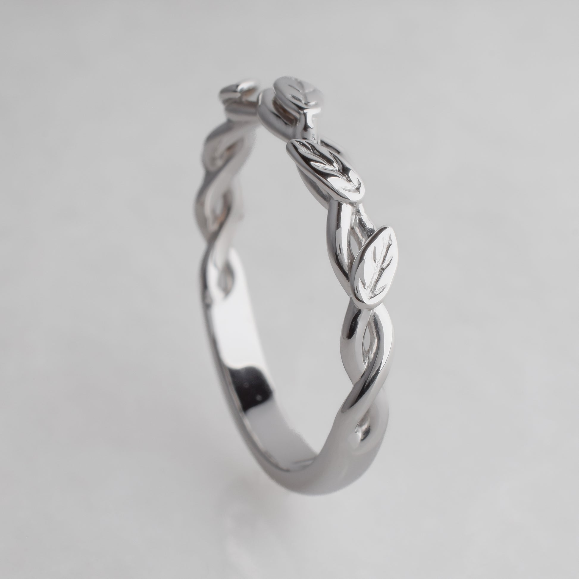 white gold  ring with leaf design on a light gray background
