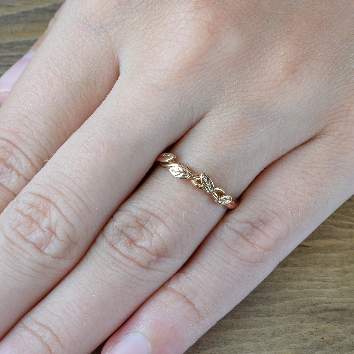 dainty leaf and vine wedding band in rose gold on finger