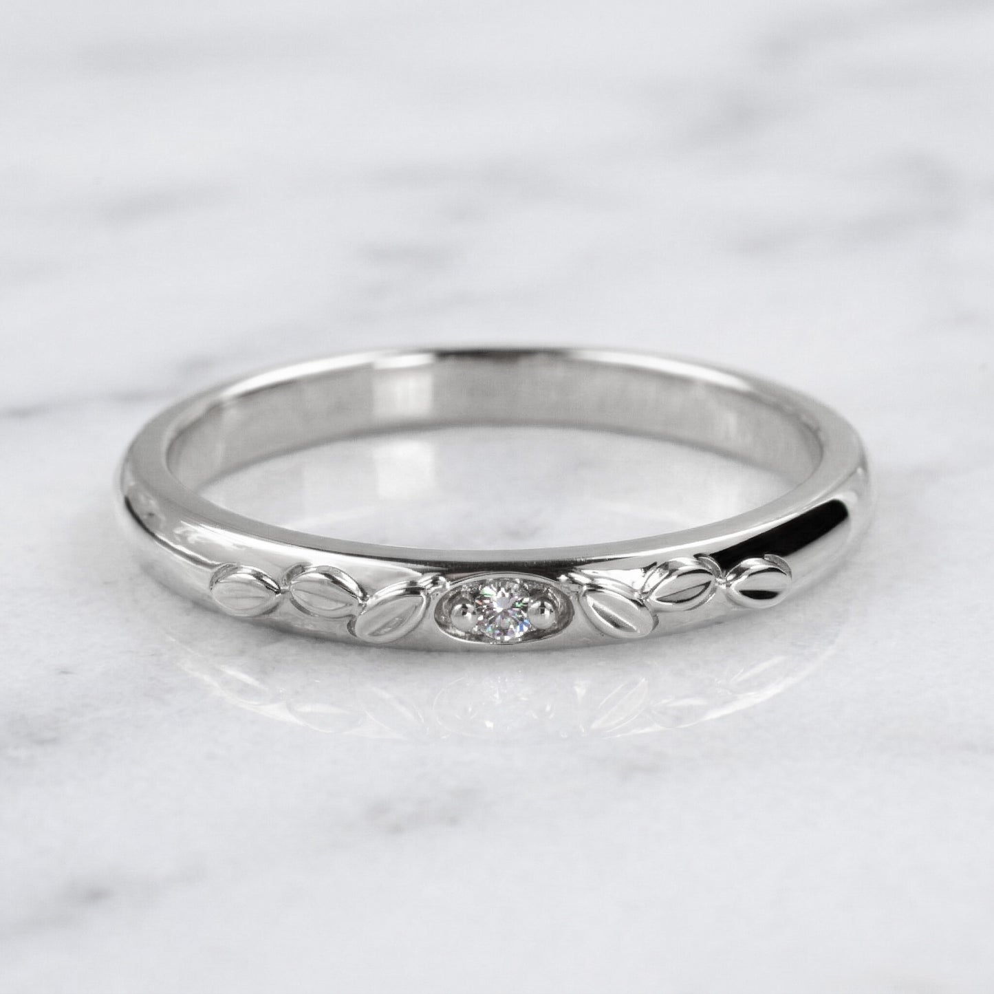 white gold ring with a diamond on a marble background