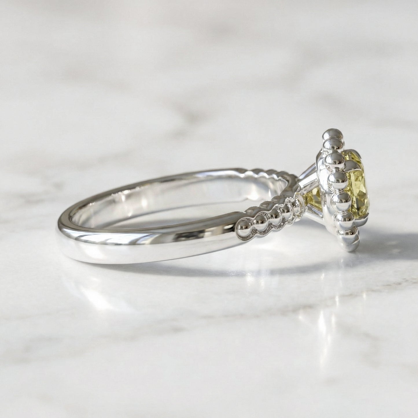 White gold ring with a yellow gemstone on a light gray background