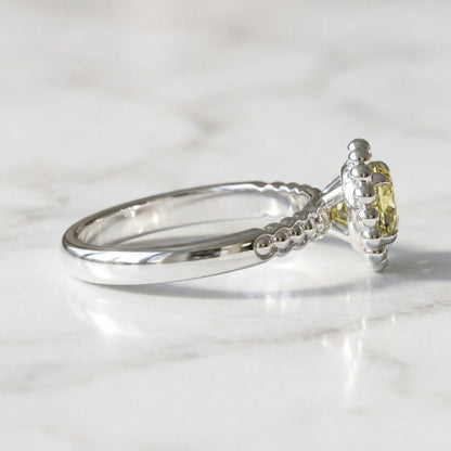 White gold ring with a yellow gemstone on a light gray background