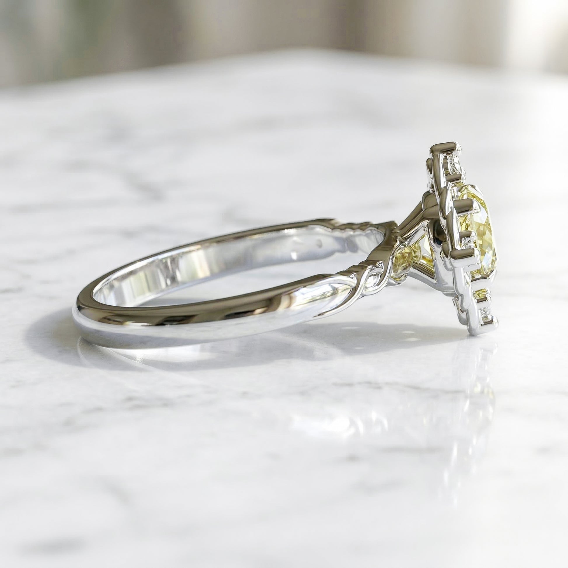 White gold ring with a yellow gemstone on a marble surface