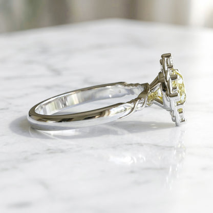 White gold ring with a yellow gemstone on a marble surface